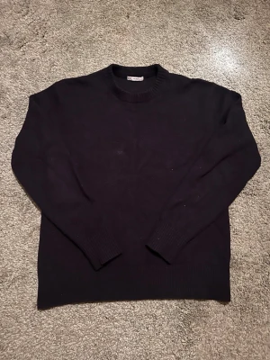 Marinblå stickad tröja i ullmix - Klassisk marinblå stickad tröja från Cubus i mjuk ullblandning. Tröjan har rund halsringning, långa ärmar och ribbade muddar vid ärmslut och nederkant. Perfekt för lager på lager och enkel att matcha med olika stilar.