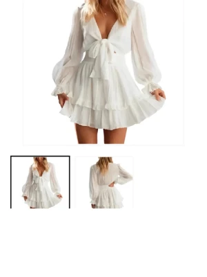 Vit klänning  - Söt vit kortklänning med omlottdesign och knyt framtill. Klänningen har volangdetaljer i kjolen och korta ärmar. Perfekt för sommarens alla tillfällen och ger en luftig och fräsch känsla. Tillverkad i ett lätt material som känns bekvämt mot huden.