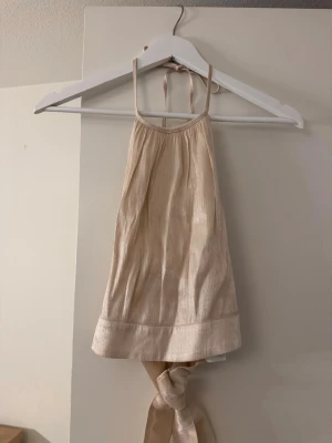 Beige ribbad linnetopp från NA-KD - Trendig beige linnetopp från NA-KD med ribbad struktur och tunna axelband. Toppen har knytband i ryggen och är ärmlös med croppad passform. 