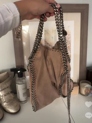 Stella Mccartney - så fin beige stella mccartney väska, sjäclkwrt äkta men inget äkthetsbevis finns tyvärr, men går säkert att kolla upp! väskan är väldigt använd och finns tydliga tecken på det. pris går att diskutera och har rabatter vid köp av bundles 💓