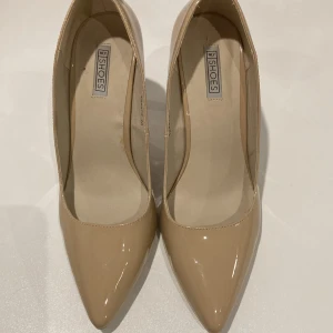 Beige pumps med spetsig tå från NLY Shoes - Säljer ett par stilrena beige pumps från NLY Shoes med hög klack och spetsig tå. Skorna har en glansig finish och klassisk design som passar perfekt till många olika outfits.
