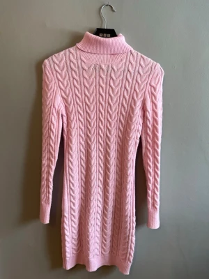 Rosa stickad poloklänning - Supersöt rosa stickad klänning med polokrage och kabelstickat mönster. Klänningen har lång ärm och är i kort modell, perfekt för dig som gillar en mysig men ändå stylish look. Passar perfekt till höst och vinter. Redan sålt en likadan och del är underbara men kommer inte till användning så ofta. Pris förslag skickas gärna