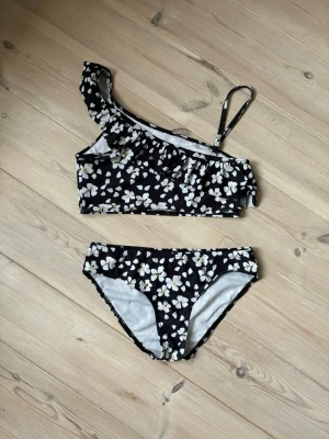 Blommigt bikiniset - Blommig bikinitop och matchande trosor. Köpt för jättelängesen och aldrig använt. Storlek: 158/164