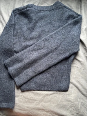 Mörkblå stickad tröja - Mysig mörkblå stickad tröja med rund hals och långa ärmar. Tröjan har en enkel, klassisk design och är tillverkad i ett mjukt, fluffigt material som känns skönt mot huden. Perfekt för kyliga dagar och enkel att matcha med olika outfits.
