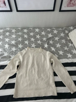 Beige stickad tröja  - En stilren beige stickad tröja. Tröjan har en rak passform och ribbade muddar vid ärmslut och nederkant. 
