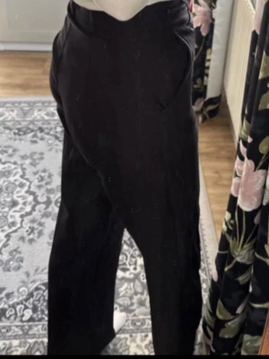 Svarta vida kostymbyxor - Säljer ett par svarta kostymbyxor med hög midja och raka, vida ben. Byxorna har fickor på sidorna och en klassisk, stilren look. Perfekta för dig som gillar en clean och trendig stil. De är lite noppiga 