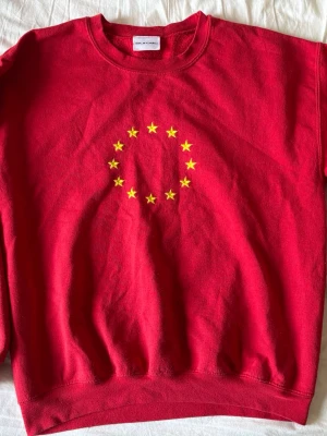 Röd sweatshirt från Eurotic - Röd sweatshirt från Eurotic med tryck av gula stjärnor i cirkel på bröstet. Klassisk rund halsringning och ribbade muddar vid ärmslut och nederkant. Perfekt för dig som gillar statement-plagg och vill sticka ut lite extra. Skitfin!