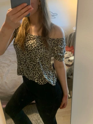 Leopardmönstrad topp - Trendig topp med leopardmönster i beige och svart. Toppen har korta ärmar och en lös passform som ger en avslappnad vibe. Perfekt för dig som vill sticka ut lite extra. Materialet känns lätt och skönt mot huden.