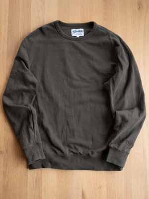Mörkgrön sweatshirt från The Stronghold - Mörkgrön sweatshirt från The Stronghold med klassisk rund halsringning och ribbade muddar vid ärmslut och nederkant. Tillverkad i mjuk bomull för en skön och avslappnad look. Perfekt för dig som gillar stilrena och tidlösa plagg.