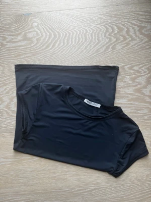 Blå tight t-shirt från Zara - En blå, tight t-shirt från Zara med rund halsringning och korta ärmar. T-shirten är enkel och stilren, perfekt att matcha med olika outfits. Materialet känns mjukt och stretchigt mot huden. Rätt så liten i stl men väldigt stretchigt material.