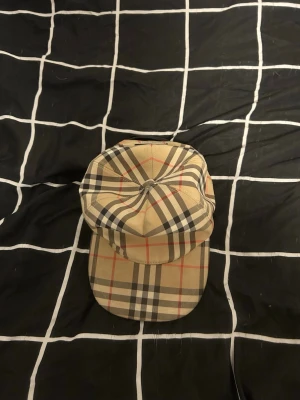 Burberry London England Keps – Strl M – Äkta & Helt Ny - Säljer en äkta Burberry London England keps i storlek M. Kepsen är helt ny och oanvänd, i perfekt skick. Den klassiska Burberry-rutiga designen tillsammans med Burberry London England-loggan ger en exklusiv och tidlös look som passar till alla outfits.  ✔️ Märke: Burberry ✔️ Modell: Burberry London England Keps ✔️ Storlek: M ✔️ Skick: Helt ny och oanvänd ✔️ 100 % äkta ✔️ Färg: Beige med klassiskt Burberry-rutigt mönster ✔️ Stilren och exklusiv design ✔️ Perfekt för både vardag och festligare tillfällen 