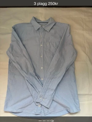 Ljusblå skjorta med klassisk krage - Snygg ljusblå skjorta med klassisk krage och knäppning framtill. Skjortan har en bröstficka och långa ärmar med manschett. Perfekt för en clean och stilren look.