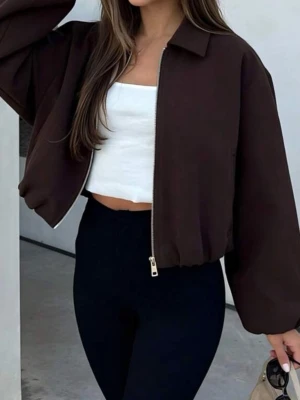 Brun croppad zip-jacka - Snygg brun croppad jacka med dragkedja framtill och breda ärmar. Jackan har en enkel krage och avslappnad passform, perfekt för en trendig streetstyle-look. Materialet ser ut att vara mjukt och bekvämt, troligen bomull eller bomullsblandning.