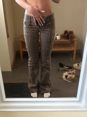 Leopardmönstrade jeans - Säljer ett par snygga leopardmönstrade bootcut jeans med låg midja från Nelly, storlek 32 men är uppsydda hos en skräddare, så de är snyggt uppsydda och inget som syns. Måtten finns på bilderna. Säljer då de tyvärr är för små för mig. Endast använda fåtal gånger.