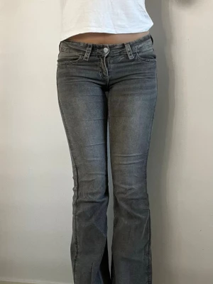 Grå bootcut jeans med fickdetaljer - Säljer ett par grå low waist bootcut jeans med snygga fickdetaljer bak. Storlek 158 alltså barnstorlek men passar xs/s. Knapparna på bakfickorna har gått av därav lågt pris!