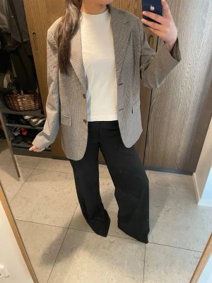 Gråmelerad oversized kavaj - Snygg kavaj med diskret rutmönster och två knappar framtill. Klassisk krage, två fickor och knappdetaljer vid ärmslut. 