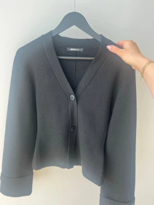 Svart kofta från Gina Tricot - Stilren svart kofta från Gina Tricot med två knappar framtill och v-ringad hals. Använd fåtal gånger. 