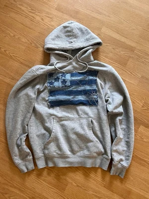 USA hoodie - En hoodie med USA flaggan som motiv gjord av mig. Flaggan är av jeans och hoodien har en distressed look. Storlek M