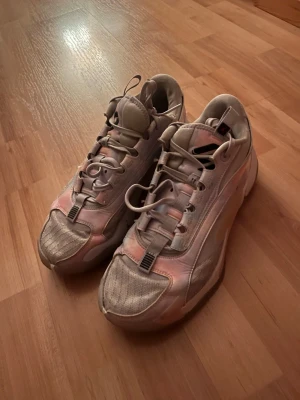 Jordan luka 2 - Säljer ett par Jordan sneakers i beige med skimrande rosa detaljer och meshpaneler. Skorna har en chunky sula med genomskinliga partier och klassisk Jumpman-logga undertill. Snygg design med robust snörning och sportig vibe.