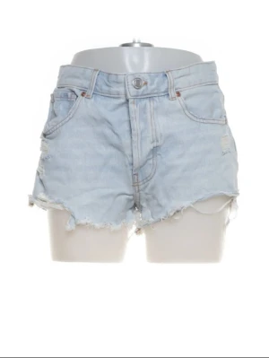 Ljusblåa högmidjade jeansshorts - Säljer ett par ljusblåa  jeansshorts med råa, fransiga kanter och slitna detaljer. Klassisk femficksmodell med knapp och dragkedja framtill. Perfekta för sommaren och riktigt snygga till sneakers eller sandaler.( VILL BLI AV MED SNABBT)