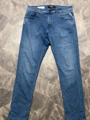 Blå jeans från Replay - Säljer ett par klassiska blå jeans från Replay med rak passform och fem fickor. Jeansen har en snygg tvättad look och Replay-logga på myntfickan. Tillverkade i mjuk denim som sitter skönt hela dagen. Perfekta till en avslappnad stil.