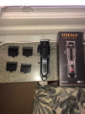 Hiena  hår clipper svart - Säljer en svart Hiena HYN-212 hårtrimmer med digital display och fyra medföljande kammar för olika längder. Clipper har ett greppvänligt handtag och laddas via USB C. Perfekt för att fixa frisyren hemma . 4 kammar 1.5 mm 3 mm 4.5 mm 6 mm