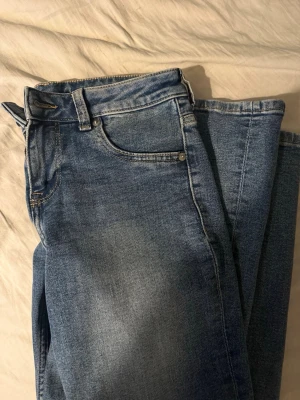 Ljusblå lowaist jeans  - Säljer ett par klassiska blå jeans med utsvängd passform. Jeansen har låg midja och är i storlek 38. Perfekta till en avslappnad stil och tillverkade i mjuk denim.