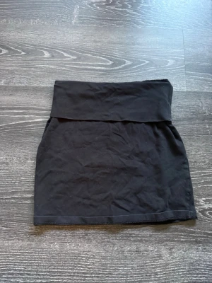 Svart kortkjol i bomull - Enkel svart kortkjol med hög midja och bred linning. Kjolen är rak i modellen och sydd i mjukt bomullstyg, perfekt att matcha med en crop top eller hoodie för en chill look.