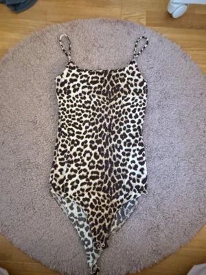 Leopardmönstrad body/topp med smala band - Säljer en leopardmönstrad body med smala axelband . Toppen har en figurnära passform och är unik Materialet känns mjukt och stretchigt, troligen polyester eller syntet.