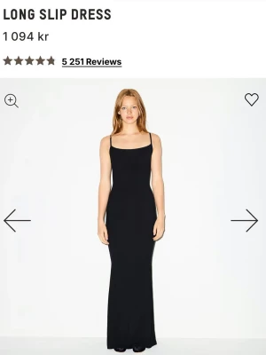 Svart klänning - Säljer en svart lång slipklänning med smala justerbara axelband och figurnära passform. Klänningen har en enkel och stilren design som ger en elegant siluett. Perfekt för dig som gillar minimalistisk stil och vill ha en klassisk bas i garderoben.