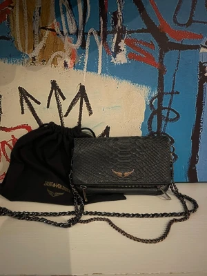 ZADIG VÄSKA ORMSKINN - Säljer min fina Zadig väska i den mindre modellen! Väskan är rätt unik då den är i ormskinn och ej i det ”vanliga” lädret! Tyvärr har den viss slitage på kedjorna men overall i fint skick, går även att byta ut kedjorna. DUSTBAG medföljer! Öppen för bud 🩷