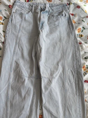 Ljusblå loose fit jeans med sömdetaljer - Säljer ett par ljusblå jeans med loose fit och raka ben. Jeansen har tydliga sömdetaljer framtill och klassiska fickor både fram och bak. Perfekta för dig som gillar en avslappnad och trendig stil.