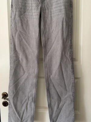 Ljusgrå raka jeans - Säljer ett par ljusgrå jeans med rak passform och klassisk femficksdesign. Jeansen har normal midja och är tillverkade i denim med en mjuk känsla. Perfekta för en avslappnad och trendig stil.