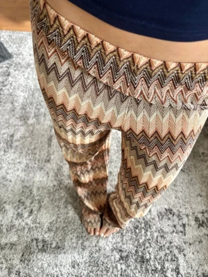 Mönstrade zigzag-leggings  - Säljer ett par snygga leggings med zigzag-mönster i beige, brunt och orange. Slutsålda och så fina till sommaren, i sttl xs men passar mig med vanligtvis s-m i byxor, stretchiga i midjan