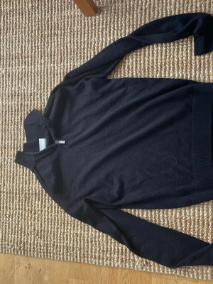 Mörkblå stickad halvzip tröja - Snygg svart stickad bruun & stengade tröja med halv dragkedja vid halsen och ribbade muddar. Perfekt för lager på lager och enkel att matcha med jeans, shorts, kostymbyxor Klassisk modell med lång ärm och hög krage. Gjord på 50% extra fin merino wool och 50% acrylic 