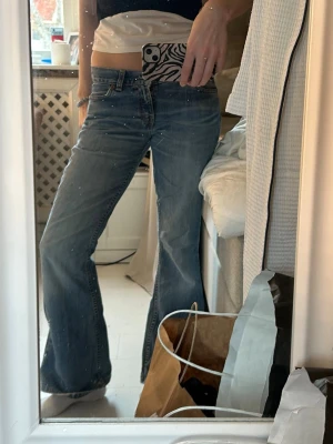 Blå bootcut jeans med låg midja Levis  - Snygga blå bootcut jeans med låg midja och klassiska fem fickor. Jeansen har en lätt tvättad look och vida ben som ger en retro vibe. Perfekta för dig som gillar en avslappnad men trendig stil.