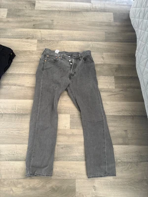 Grå Levi's 501 jeans raka ben - *pris kan diskuteras* Säljer ett par klassiska grå Levi's 501 jeans med raka ben och knappgylf. Jeansen har fem fickor och är tillverkade i slitstark bomull. Perfekta för en avslappnad och trendig look. Lite för taight men helt nya och nästan ovanvänd bara för att jag har testat dem på. 
