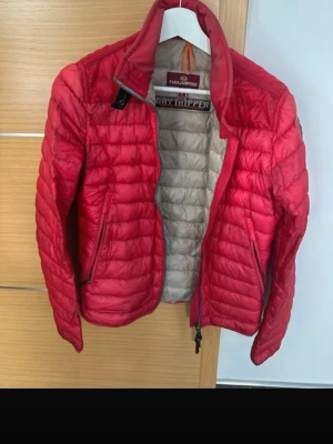 Rosa dunväst från Parajumpers S - Snygg rosa dunväst från Parajumpers med quiltad design och dragkedja framtill. Insidan är beige och västen har två fickor med dragkedja. Perfekt för lager på lager och ger en sportig vibe till din outfit.