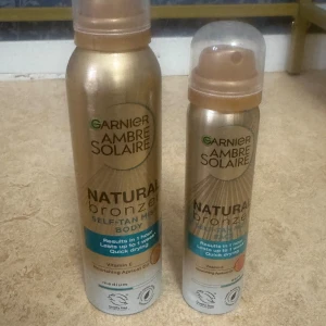 Garnier Ambre Solaire Natural Bronzer - Två flaskor Garnier Ambre Solaire Natural Bronzer Self-Tan Mist för kroppen. Färgen är medium och produkten kommer i sprayform med guldiga flaskor och transparenta lock. Innehåller vitamin E och aprikoskärnolja för en naturlig solkysst look.