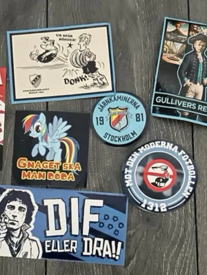 Samling Djurgården-klistermärken - Säljer en samling klistermärken med Djurgården-tema. Motiven inkluderar tecknade figurer, slogans och supporterbudskap i färgerna blå, gul, svart och vit. Perfekt för dig som vill pimpa laptop, cykel eller anteckningsbok med DIF-prylar.