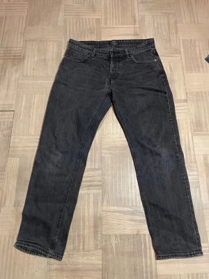 Svarta raka jeans - Säljer ett par svarta jeans med rak passform och klassisk femficksdesign. Jeansen har normal midja och stängs med dragkedja och knapp. Materialet är denim i bomull. Perfekta till en avslappnad stil.