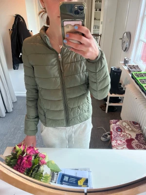 Olivgrön pufferjacka med dragkedja - UNIQLO LIKNANDE 💚🍀🤍Säljer en olivgrön pufferjacka med hög krage och dragkedja framtill. Jackan har en quiltad design och två sidofickor. Perfekt för kalla dagar och ger en clean, stilren look. Materialet är lätt och känns skönt att bära. Passar xs->s🤍