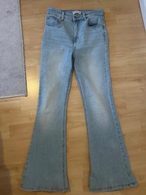 Ljusblå bootcut jeans passar både storlek 36/38  - Säljer ett par ljusblå bootcut jeans med klassisk femficksmodell och hög midja. Jeansen har utsvängda ben och är tillverkade i ett mjukt denimtyg. Perfekta för en avslappnad och trendig look.