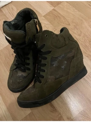 Gröna camo high top skor - Snygga high top sneakers i grönt kamouflagemönster på sidorna och svarta skosnören. Storlek 38