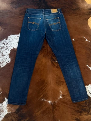 Selvage Nudie SteadyEddie II - Tjena! Säljer dessa riktigt snygga straight tapered nudie jeans, byxorna är i selvage och är i passformen steadyeddie 2, W31/L34, modellen brukar ha w33/l34 men passar ändå då byxorna är otvättade och kommer att krympa första gången dom blir tvättade, hör av dig vid funderingar!🙌   på bild 6 ser du en sömm som jag aldrig sätt på ett par nudies förut, detta gör mig lite osäker på äktheten även fast allt annat ser 100% äkta ut, detta är varför byxorna är lite billigare