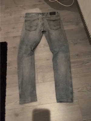 Replay anbass - Säljer ett par ljusblå slim fit jeans med slitna detaljer och klassiska fem fickor. Jeansen har raka ben och en tvättad look som ger en avslappnad vibe. Perfekta för dig som gillar en enkel men snygg stil. 32/34