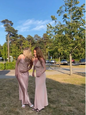 Rosa balklänning  - Säljer min balklänning i ljusrosa med djup v-ringning och smala axelband. Klänningen har en figurnära passform och faller snyggt längs kroppen med en snörning i ryggen. 