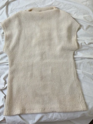 Ribbad ärmlös topp från Gina Tricot - Säljer en krämvit ribbad topp från Gina Tricot. Toppen är ärmlös med en rak, något längre passform och rund halsringning. Perfekt att styla med jeans eller kjol för en clean look. Skriv om ni är intresserad💕