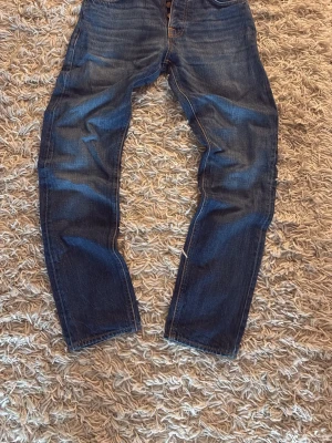 Blå jeans från Nudie Jeans - Säljer ett par snygga blå jeans från Nudie Jeans i storlek 29/32. De är i bra skick. Pris kan diskuteras!