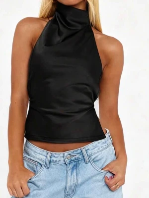 Svart halterneck topp med rosett - Trendig svart halterneck topp i satinliknande material med hög krage och öppen rygg. Toppen knyts i nacken med en stor rosett och har smala band i ryggen för en snygg passform. Perfekt för dig som vill sticka ut med en stilren och modern look.